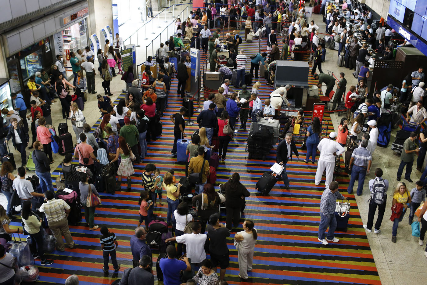 Passengers line up for the security checkpoint at Simon Bolivar airport in La Guaira, outside Caracas October 15, 2013. President Nicolas Maduro's government plans to use fingerprint machines at airports to try to root out no-shows who buy tickets to scam travel-related currency controls without even flying, in the latest symptom of Venezuela's economic chaos. REUTERS/Carlos Garcia Rawlins (VENEZUELA - Tags: POLITICS)